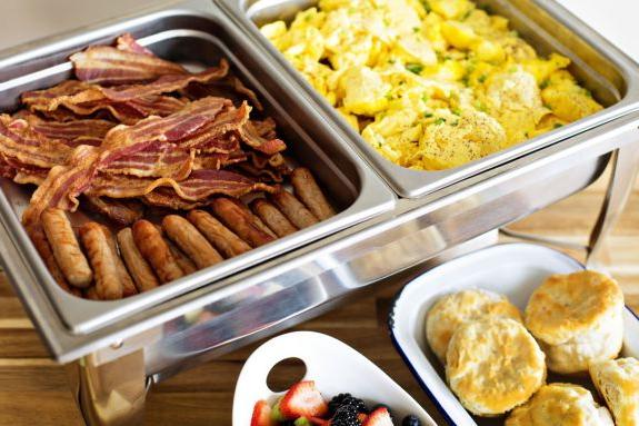 An image of eggs, bacon, fresh fruit and breakfast rolls 