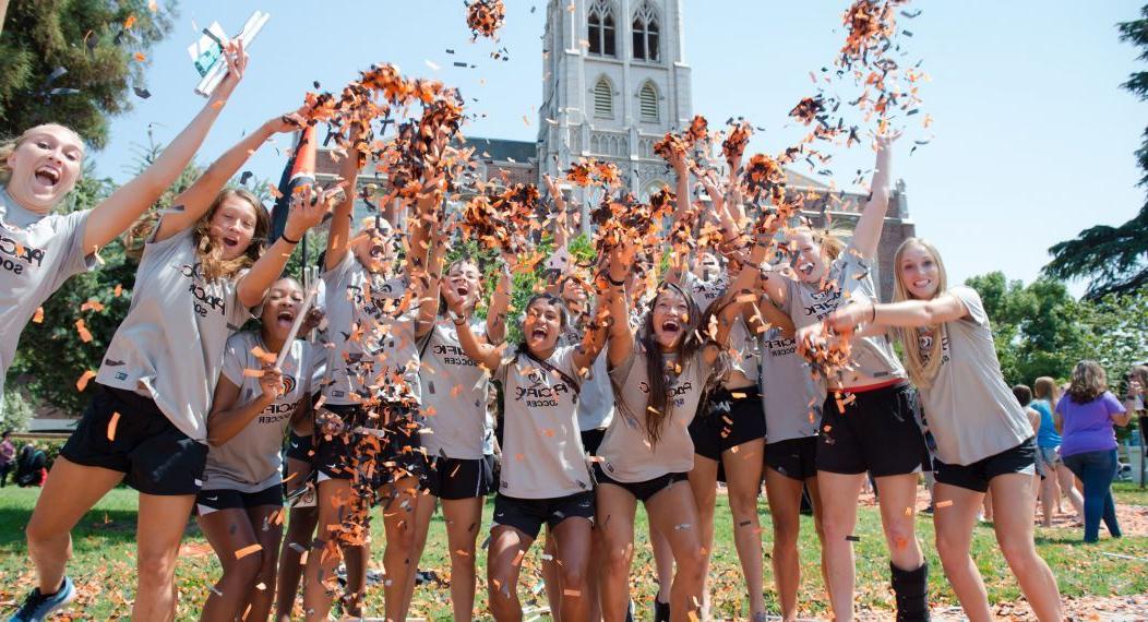 large group of students throwing confetti outdoors