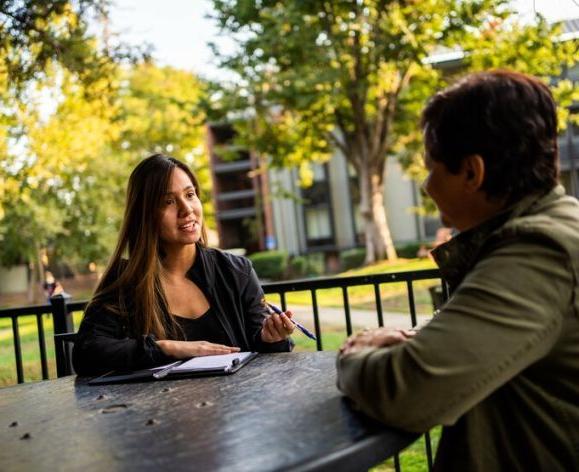 图为两名学生在萨克拉门托校园的户外桌子上聊天.